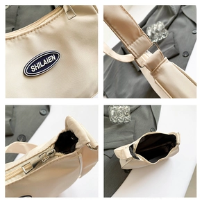 Detail view of cream nylon shoulder bag featuring logo patch, silver zipper and strap