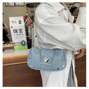 Detail of light blue croc-embossed shoulder bag with silver heart buckle and metal studs
