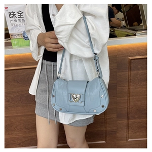 Close-up of light blue crocodile texture shoulder bag with heart buckle and silver rivets