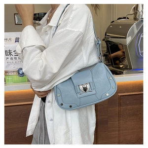 Detail of light blue crocodile pattern underarm bag with silver heart buckle and studs