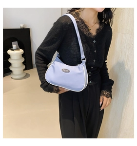 Close-up of light blue crescent hobo bag with white contrast piping and metal logo