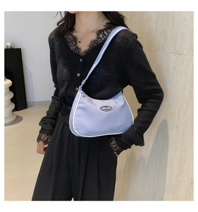 Chic light blue crescent underarm bag with white piping and logo detail on model