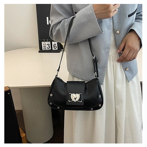 Detail of crocodile pattern shoulder bag with silver heart buckle and metal rivets