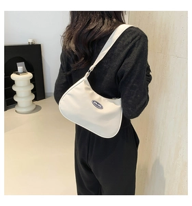 Detail shot of a beige nylon baguette bag with SHILAIEN logo worn on the shoulder