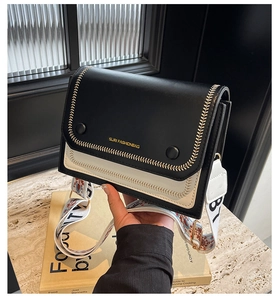 Detail of contrast crossbody bag with golden SURI FASHIONBAG logo and wide ethnic strap