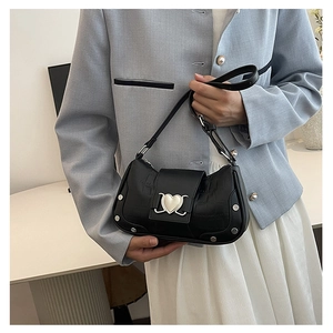 Detail of black faux crocodile leather underarm bag with silver heart metal buckle