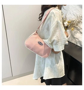 Detail view of pink crescent underarm bag with white contrast trim and branding