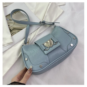 Detail of light blue crocodile texture bag with heart buckle and silver rivets