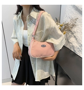 Asian model wearing a pink nylon hobo bag with a minimalist curved design and shoulder strap