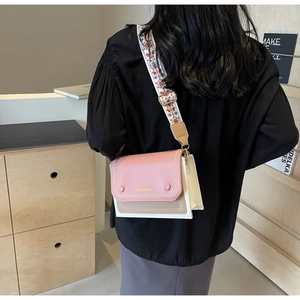 Detail of floral embroidered wide strap and color-block crossbody bag on a model