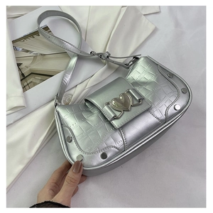 Detail of silver crocodile-embossed leather underarm bag with metal studs and heart buckle