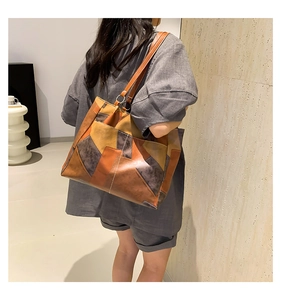 Detailed view of color-block patchwork tote bag with contrast stitching and metal ring