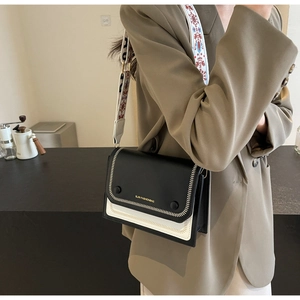 Detail of contrast stitch on black and white flap bag with wide ethnic shoulder strap