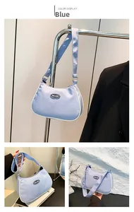 Detail view of light blue nylon crescent bag with white piping and logo detail