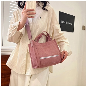 Detail of pink corduroy tote bag featuring large front pocket and adjustable shoulder strap