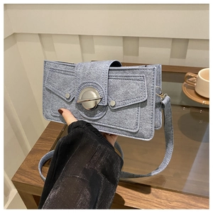 Detail of light blue textured crossbody bag with silver metal lock and double pockets