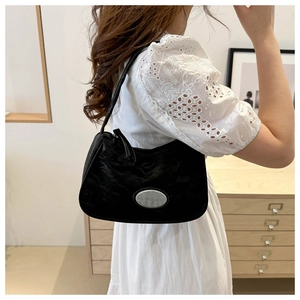 Detail of a black nylon crescent shoulder bag with silver metal logo and minimalist design