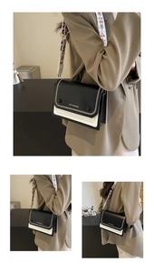 Detail of black and white leather crossbody bag featuring contrast stitching and wide strap