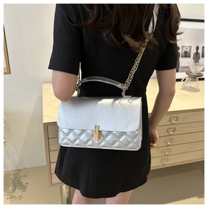 Details der silbernen Stepptasche aus Leder mit Goldschloss und Kettenriemen am Modell