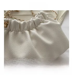 Close-up of white lychee pattern leather bucket bag with pleated drawstring closure and chain