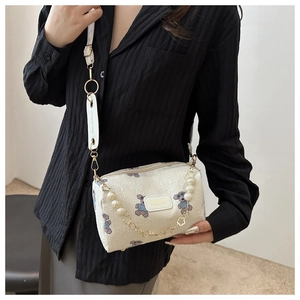 Close-up of white cylindrical bag with pearl chain and purple cartoon bear print