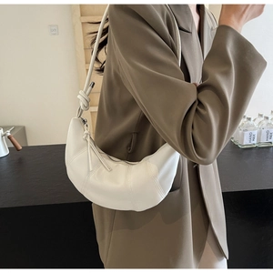Detail of white half-moon bag featuring vertical stitching and a knot shoulder strap