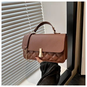Detailansicht der braunen Stepptasche aus Kunstleder mit Goldschnalle und Kettengurt