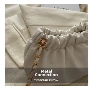 Detail of gold metal chain link on white lychee grain leather drawstring bucket bag