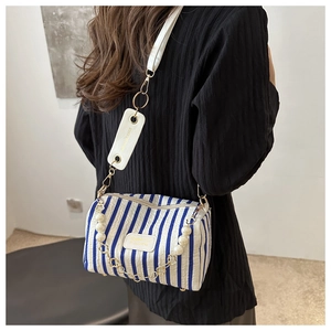Detail of blue striped cylinder bag with pearl chain and leather shoulder strap on model