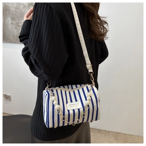 Detail of blue striped cylinder bag featuring a pearl strap and floral metal accents