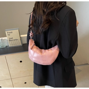 Pink crescent shoulder bag with vertical stitching and knotted strap shown on model