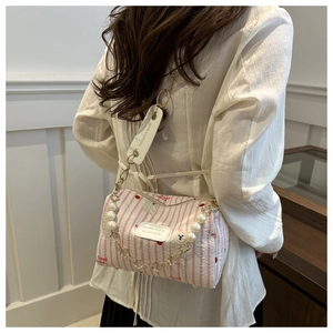 Detail of cylinder crossbody bag featuring pearl chain and Universe & Love label