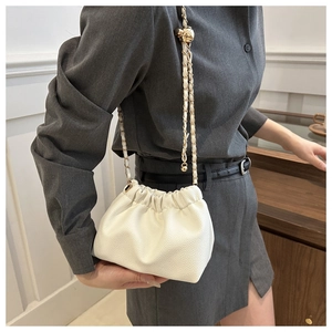 Close-up of white lychee texture leather bucket bag with gold chain and metal ball detail