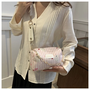 Détail du sac cylindre à rayures roses avec chaîne en perles et motifs panda cerise