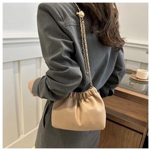 Detail view of beige ruched dumpling bag with gold chain strap and lychee leather texture