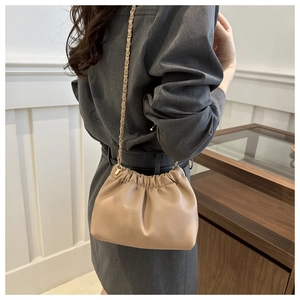 Beige drawstring bucket bag with gold chain strap in soft pebbled leather finish