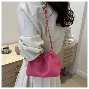 Detail of rose pink drawstring bucket bag with gold chain strap on white outfit