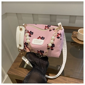 Detail of pink cylinder crossbody bag featuring pearl chain and cat floral pattern