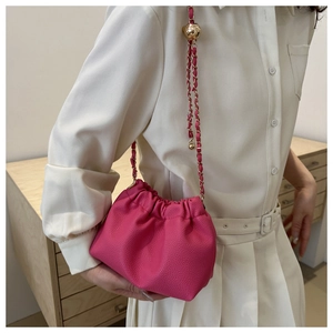 Detail of rose red drawstring bucket bag with litchi texture and gold chain strap