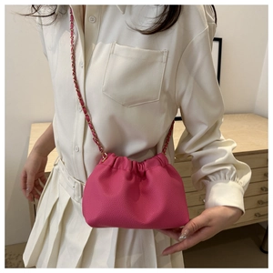Detail of rose pink drawstring bucket bag with litchi texture and gold chain strap