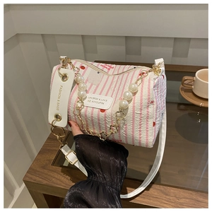 Detail of floral cylinder bag with pearl chain and cherry print on nylon fabric