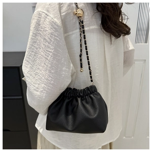 Detail of black pleated cloud bag with golden ball buckle and chain shoulder strap