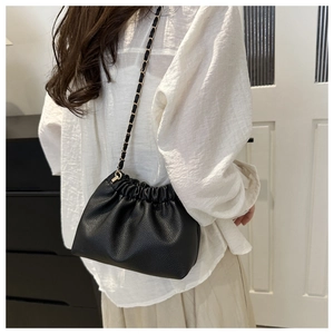 Detail of soft black lychee texture crossbody bag with gold chain and woven strap