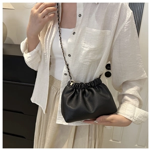 Women's black pebbled leather drawstring bucket bag with a stylish metal chain strap