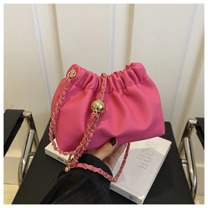 Close-up of pink drawstring bucket bag featuring lychee grain leather and gold chain
