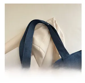 Détail de l'anse d'un sac en jean bleu avec bordure en dentelle blanche et tissu denim
