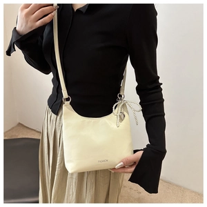 Détail du sac hobo jaune pâle avec nœud en perles et pendentif en forme de cœur