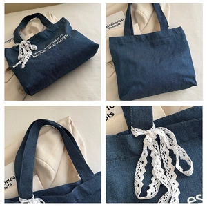 Détail du sac cabas en jean bleu avec nœud en dentelle blanche et texte imprimé