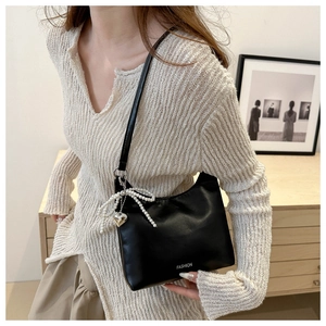 Détail du sac à bandoulière noir avec nœud en perles et pendentif cœur en argent