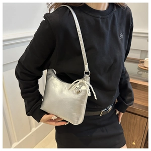 Détail du sac sous l'aisselle argenté métallisé avec glands en perles et breloque cœur